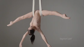 Naked aerial yoga with a slim brunette spreading her legs wide in a silk hammock